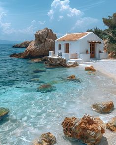 a white house sitting on top of a sandy beach next to the ocean with blue water