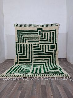 a large green and white rug on top of a wooden floor next to a wall