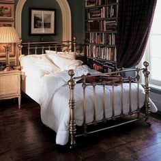 a bed sitting in a bedroom next to a book shelf filled with lots of books