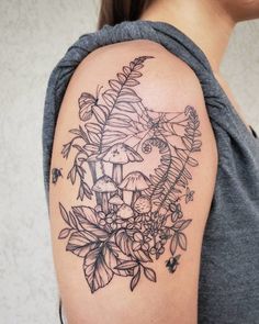 a woman with a tattoo on her arm has flowers and mushrooms in the middle of it