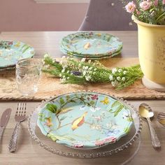 the table is set with plates, silverware and flowers