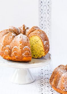 a bundt cake with powdered sugar on top sits on a plate next to another bundt cake