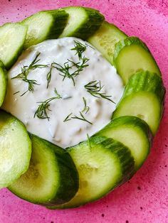 cucumber slices arranged around a bowl with ranch dressing in it on a pink plate