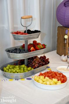 three tiered trays filled with different types of fruits and vegetables on a table