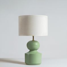 a green table lamp with a white shade on it