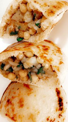 two pita breads with chickpeas and spinach on top, one cut in half