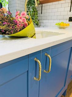 a kitchen with blue cabinets and flowers on the counter top, next to a sink