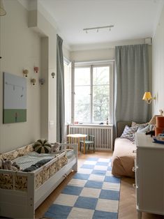 a bedroom with two beds and a desk in front of a large window on the wall