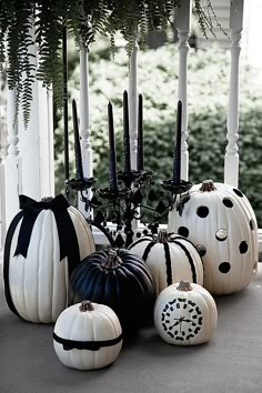 white pumpkins with black bows and candles are on the front porch for halloween decor