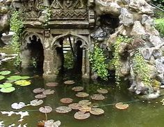 an old building is surrounded by water lilies and rocks in the middle of a pond