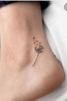 a small dandelion tattoo on the side of a woman's foot,