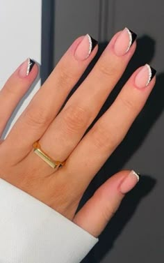 a woman's hand with black and white manies on it, holding a gold ring