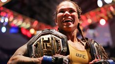 a woman in a yellow shirt holding a wrestling belt