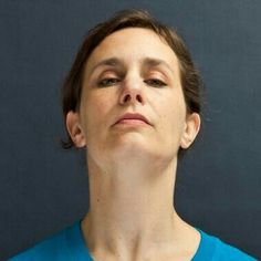 a woman with her eyes closed looking up to the sky while wearing a blue shirt