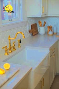 a kitchen with white cabinets and gold faucets on the counter top, along with yellow lights