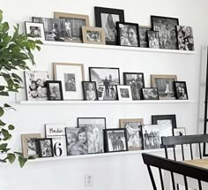 a dining room table and chairs with pictures on the wall above them, along with framed photos