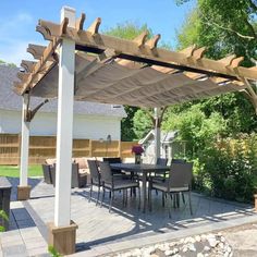 an outdoor dining area with table and chairs under a pergolated roof in the backyard