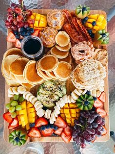 a wooden platter filled with pancakes, fruit and other foods next to a cup of coffee