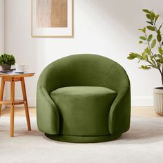 a green chair sitting in a living room next to a table and potted plant