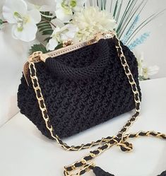 a black crocheted purse with gold chains on the handle and chain at the bottom