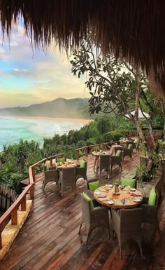 an outdoor dining area overlooking the ocean with tables and chairs set up for two people