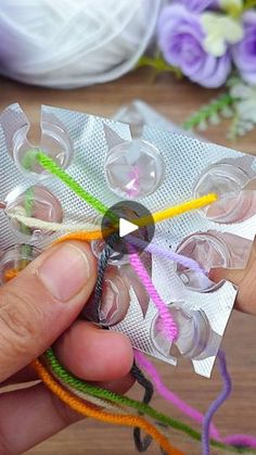 a person is holding some string and scissors in their hand while they are making something out of plastic