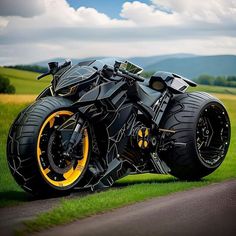 a black and yellow motorcycle parked on the side of a road in front of green grass