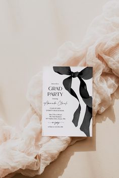 an elegant black and white wedding card with a ribbon on it sitting on a bed