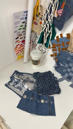 several pieces of clothing sitting on top of a white table next to a paper cup