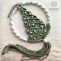 a crocheted christmas tree ornament on a white blanket with green string