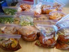 several plastic bags filled with food sitting on top of a wooden table next to each other