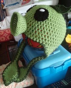 a crocheted green hat sitting on top of a blue container