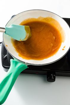 the sauce is being stirred by a spatula in a pan on top of an electric stove