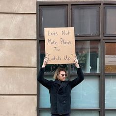 a man holding up a sign that says let's not make plans to catch up