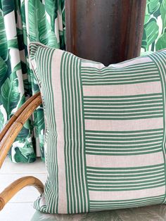 a green and white striped pillow sitting on top of a chair next to a window