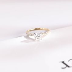 a white diamond ring sitting on top of a piece of paper