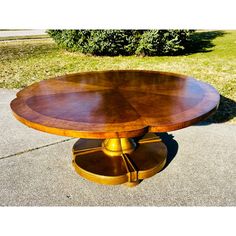 a wooden table sitting on top of a cement ground next to a grass covered field