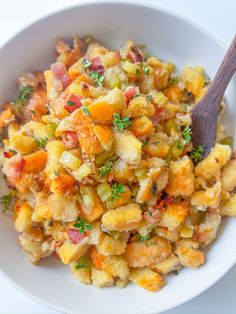 a white bowl filled with stuffing next to a wooden spoon