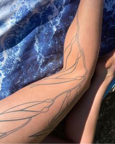 a person laying on the ground with their legs crossed and tattoos drawn on her leg