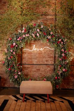 a floral wedding arch with the word love written in cursive writing on it