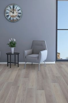 a living room with a clock on the wall next to a gray chair and table