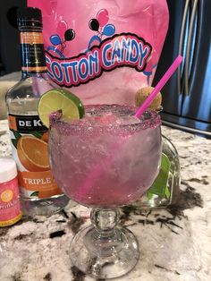 a pink drink in a glass next to an ice bag and bottles on a counter