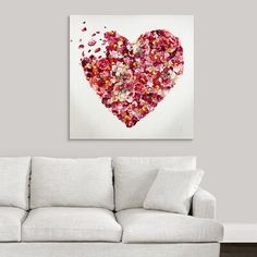 a living room with a white couch and a large heart shaped painting on the wall