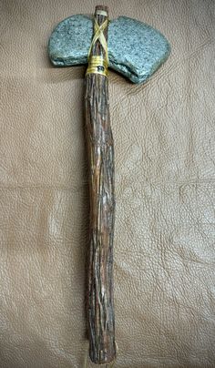 a wooden stick with a stone on top of it next to a brown leather surface