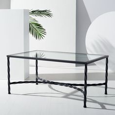 a glass table sitting in front of a wall with a potted plant on it