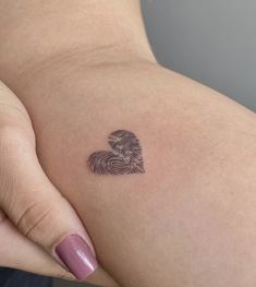 a woman's arm with a tattoo on it that has a fingerprint in the shape of a heart