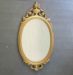 an ornate gold framed mirror hanging on the side of a gray wall with wood paneling