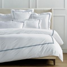 a bed with white sheets and pillows in a room