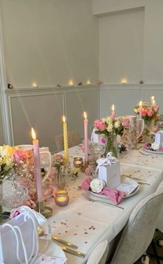 a table set for a formal dinner with candles and napkins on the table in front of it