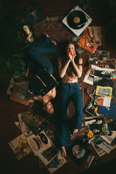 two people laying on the floor surrounded by records, cds and other things that are scattered around them